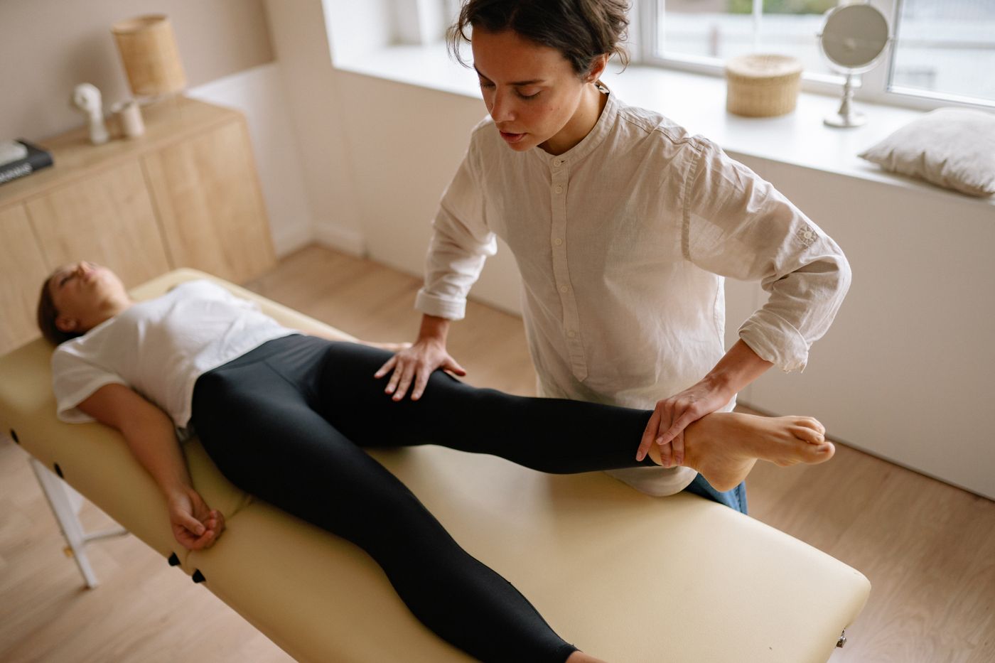 A physiotherapist assisting a patient with a rehabilitation exercise in a treatment room