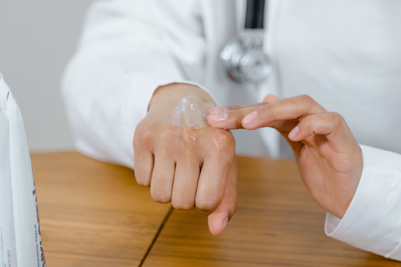 A clinician applying lotion to a patient's hand during a consultation