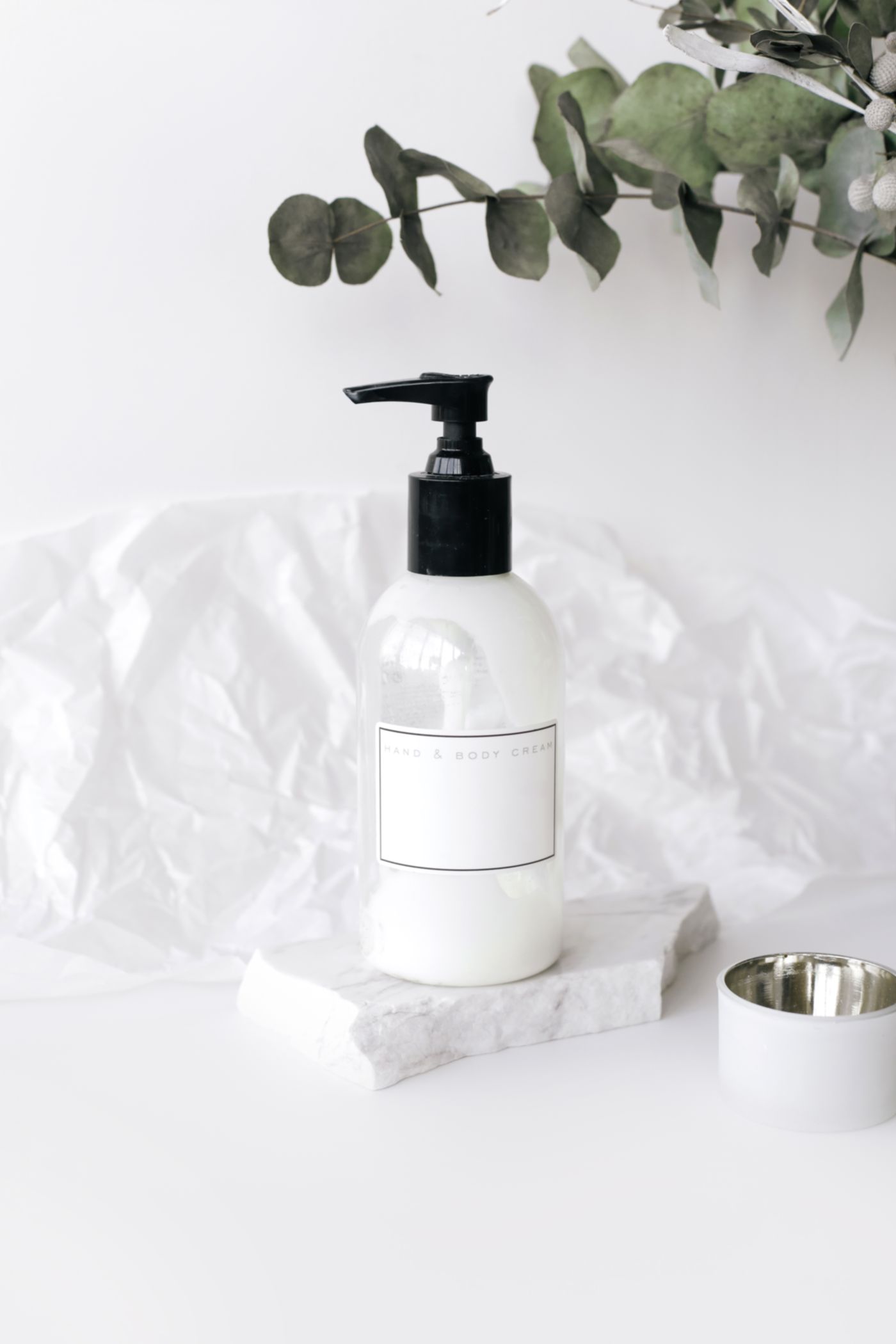 Elegant skincare bottle on a marble surface with greenery