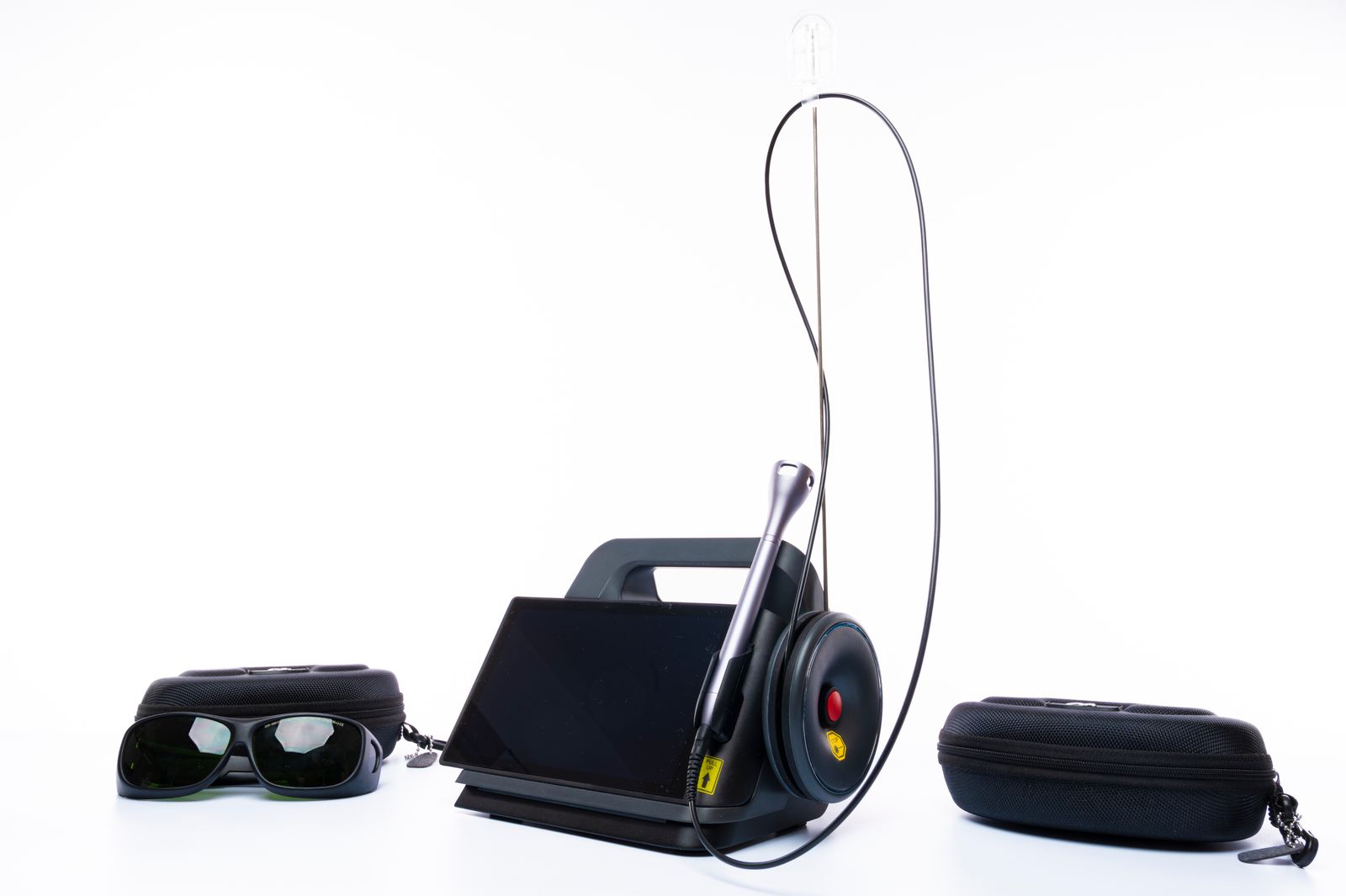 A portable laser therapy device with protective eyewear and its carrying cases, ready for a clinic session — stock photography, not an actual Plus253 device